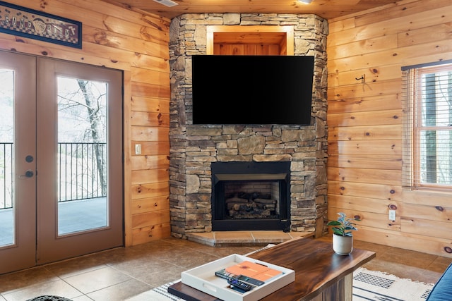 tiled living room featuring french doors, a wealth of natural light, a fireplace, and wooden walls