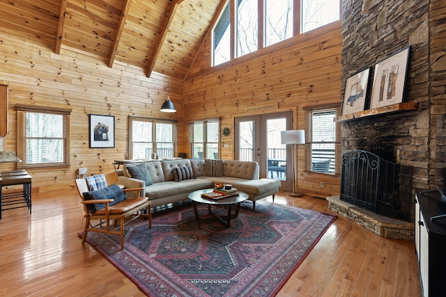 living room featuring a stone fireplace, light hardwood / wood-style flooring, high vaulted ceiling, and a wealth of natural light