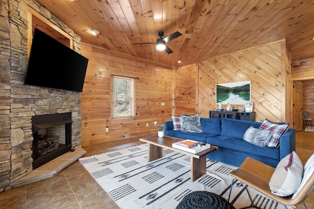 unfurnished living room with wood ceiling, a stone fireplace, wooden walls, and ceiling fan