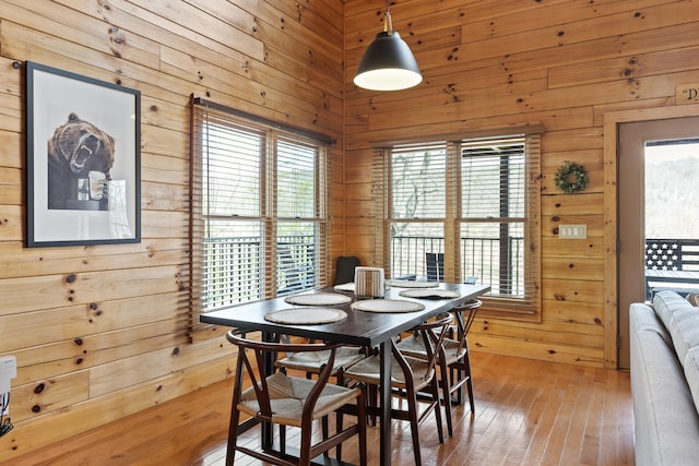 dining space with wood-type flooring and wooden walls