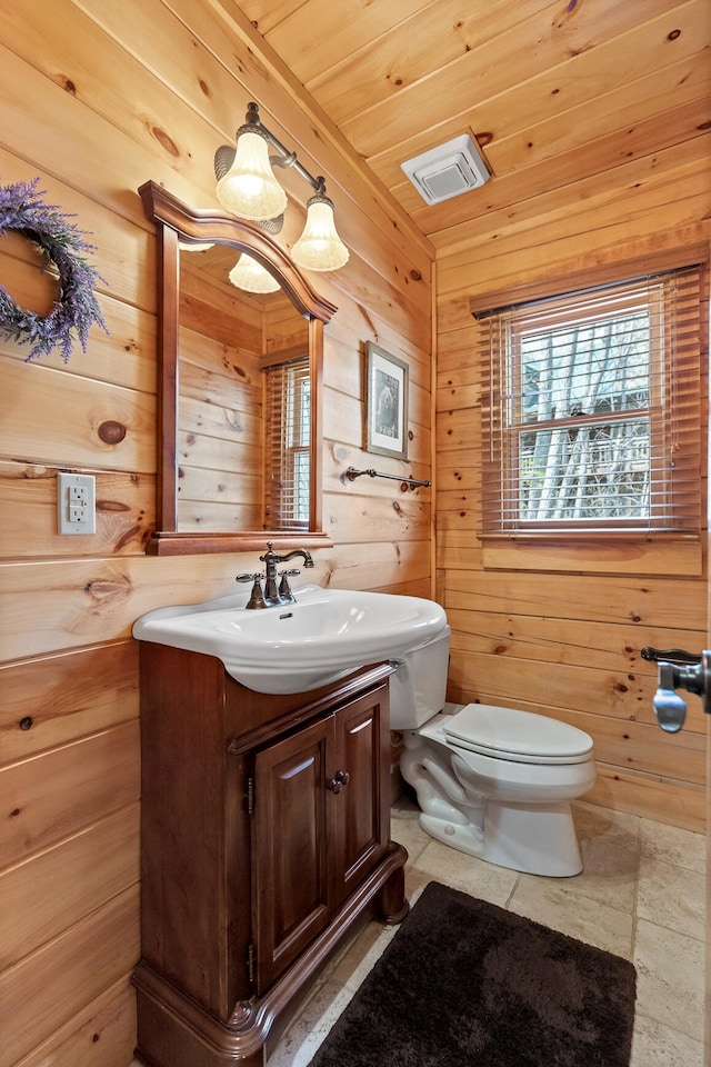 bathroom featuring wood walls, wooden ceiling, vanity, and toilet