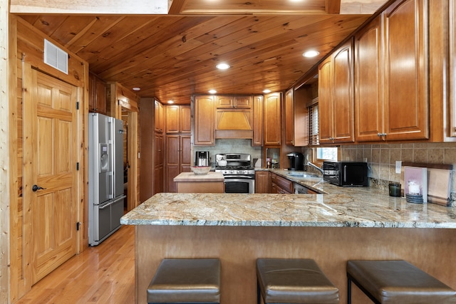 kitchen featuring light hardwood / wood-style floors, stainless steel appliances, kitchen peninsula, and a kitchen breakfast bar