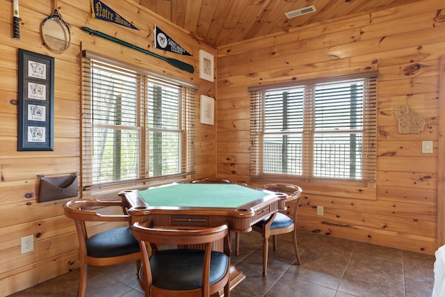 game room with wood ceiling, wooden walls, dark tile patterned flooring, and a healthy amount of sunlight