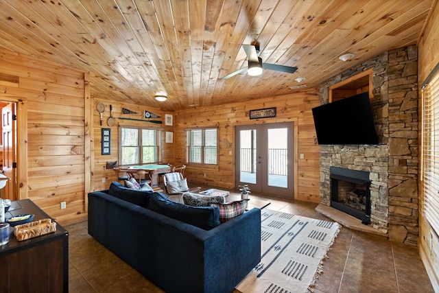 tiled living room with ceiling fan, wood ceiling, and wood walls