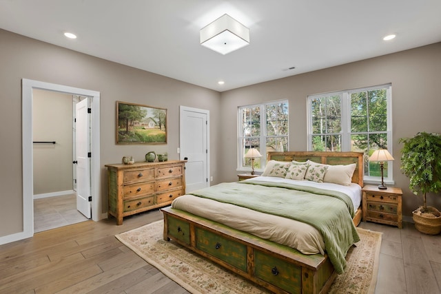 bedroom with light wood-type flooring and ensuite bath