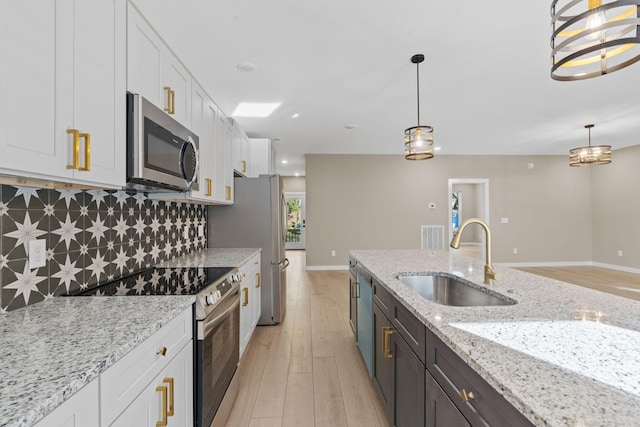 kitchen with white cabinetry, sink, hanging light fixtures, and appliances with stainless steel finishes