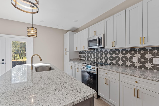 kitchen featuring sink, white cabinets, pendant lighting, and appliances with stainless steel finishes