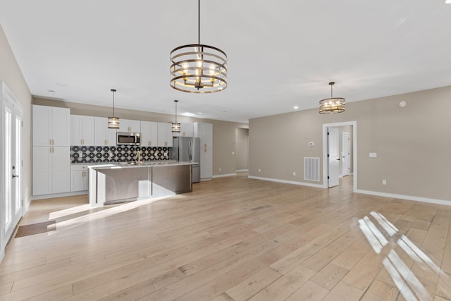 unfurnished living room featuring light wood-type flooring and an inviting chandelier