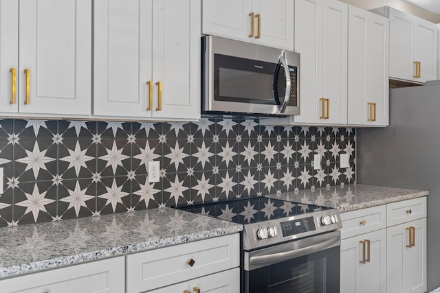 kitchen featuring tasteful backsplash, light stone counters, white cabinets, and appliances with stainless steel finishes