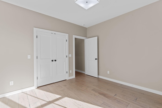 unfurnished bedroom with light wood-type flooring and a closet