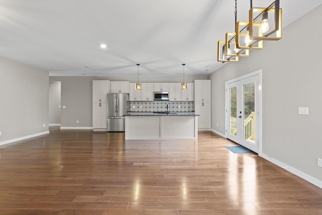 kitchen featuring white cabinets, decorative light fixtures, backsplash, and appliances with stainless steel finishes