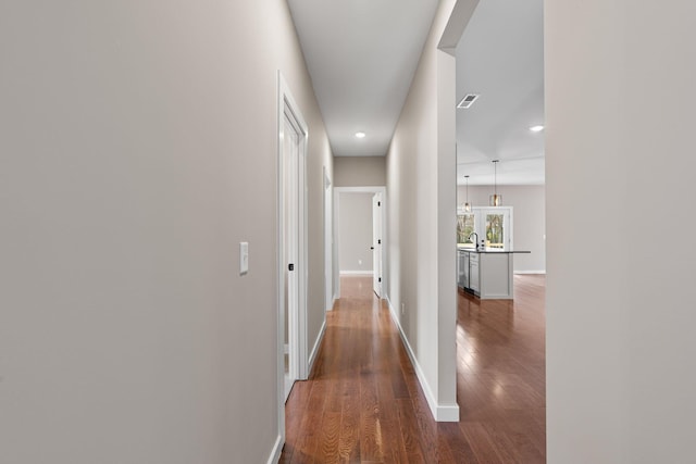 corridor with dark wood-type flooring and sink