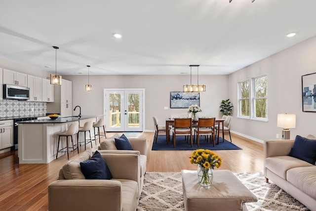 living room with french doors, light wood-type flooring, and a notable chandelier