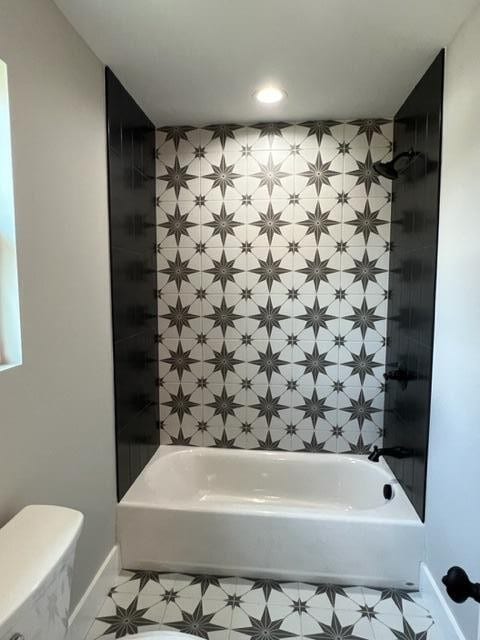 bathroom with tiled shower / bath combo and toilet