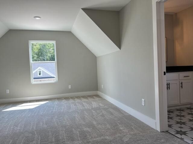 additional living space featuring lofted ceiling and light colored carpet