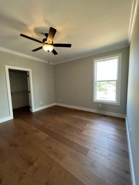 spare room with ceiling fan, dark wood-type flooring, and crown molding