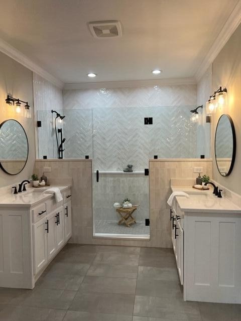 bathroom with crown molding, a shower with door, tile walls, and vanity