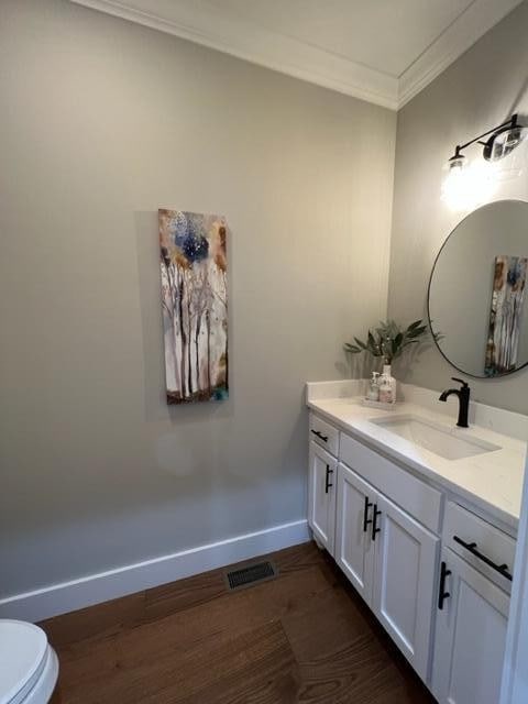 bathroom featuring ornamental molding, hardwood / wood-style floors, vanity, and toilet