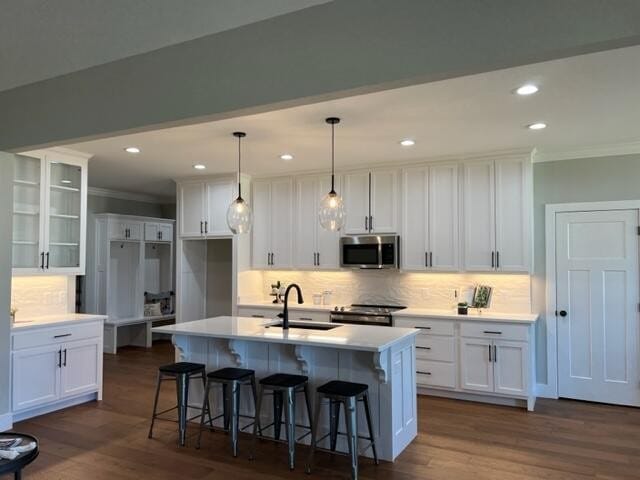 kitchen featuring a center island with sink, appliances with stainless steel finishes, dark hardwood / wood-style flooring, and white cabinetry