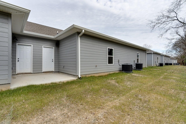 view of side of property featuring a patio, a yard, and cooling unit