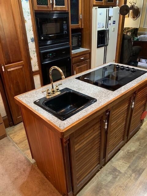 kitchen featuring an island with sink, black appliances, and sink