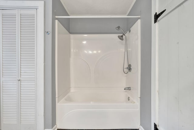 bathroom featuring a textured ceiling, bathtub / shower combination, and ornamental molding