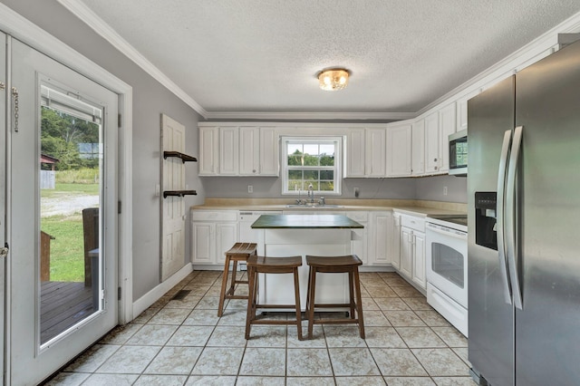 kitchen with appliances with stainless steel finishes, white cabinetry, a breakfast bar area, a center island, and sink