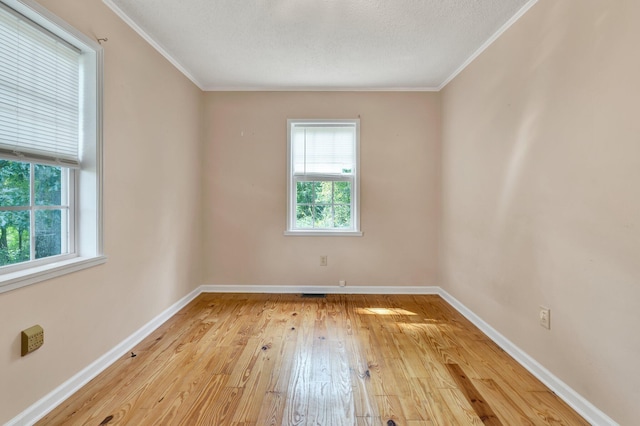 spare room with a textured ceiling, ornamental molding, and light hardwood / wood-style flooring