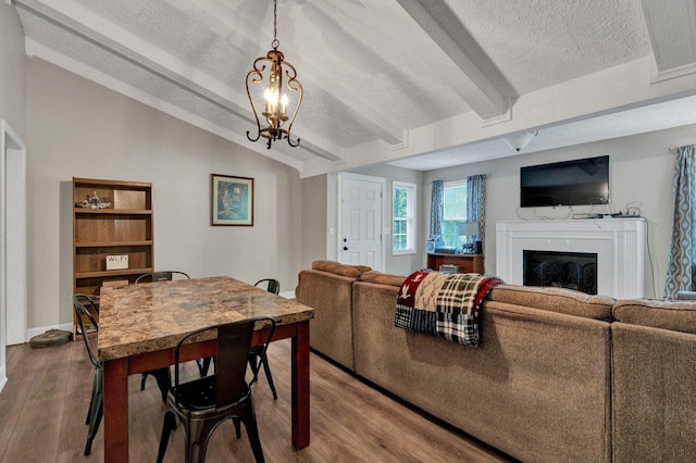 dining area featuring vaulted ceiling with beams, an inviting chandelier, light wood-type flooring, and a textured ceiling