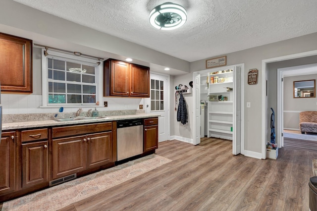 kitchen with light wood-type flooring, a textured ceiling, dishwasher, and sink