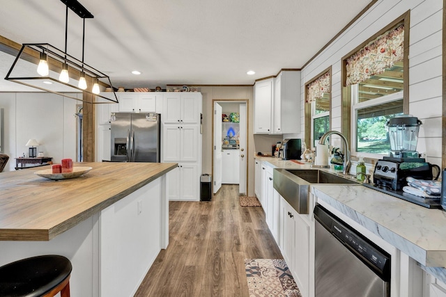 kitchen featuring pendant lighting, sink, white cabinetry, appliances with stainless steel finishes, and light wood-type flooring