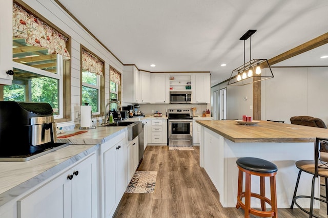 kitchen with a breakfast bar, sink, white cabinets, appliances with stainless steel finishes, and decorative light fixtures