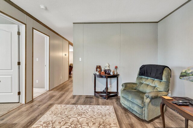 sitting room featuring a textured ceiling, crown molding, and hardwood / wood-style floors