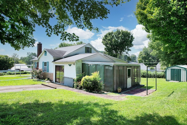 view of front of property featuring a shed, a sunroom, and a front yard