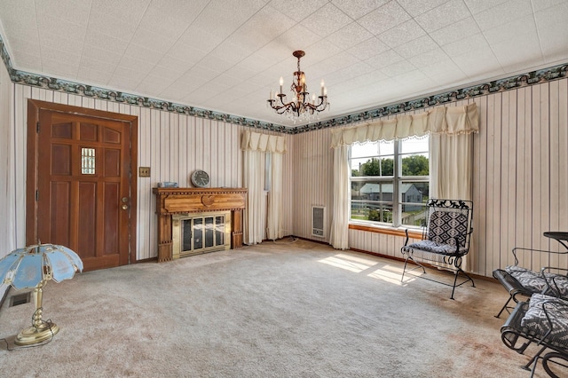 living area with an inviting chandelier, heating unit, and carpet flooring