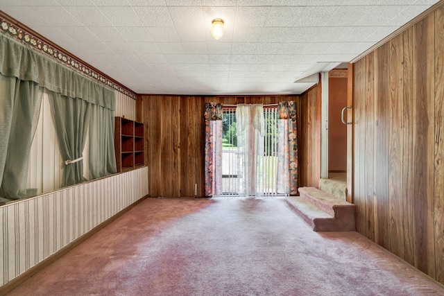 carpeted spare room with wood walls and crown molding