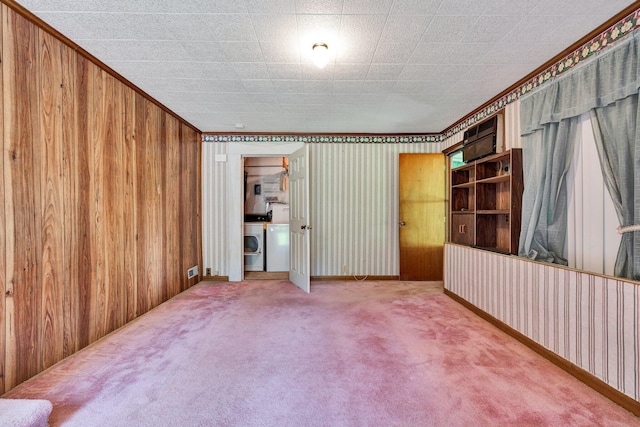 unfurnished bedroom with crown molding, carpet, wood walls, and washer and clothes dryer