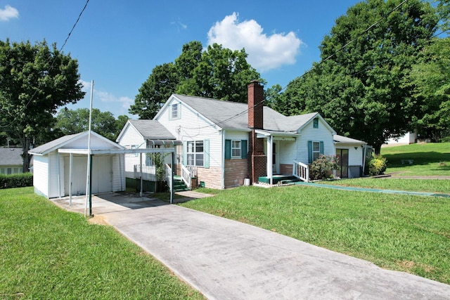 view of front of house with a front yard, a carport, and an outbuilding