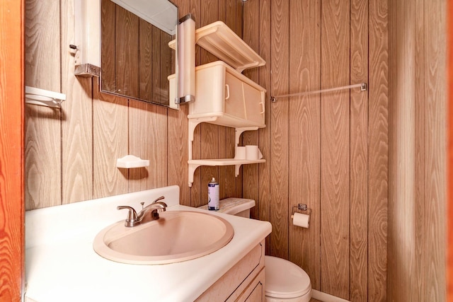 bathroom featuring wooden walls, vanity, and toilet