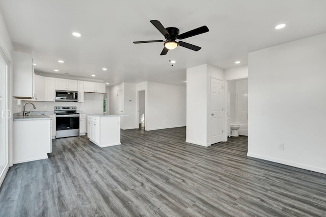 kitchen with ceiling fan, wood-type flooring, white cabinets, appliances with stainless steel finishes, and a center island