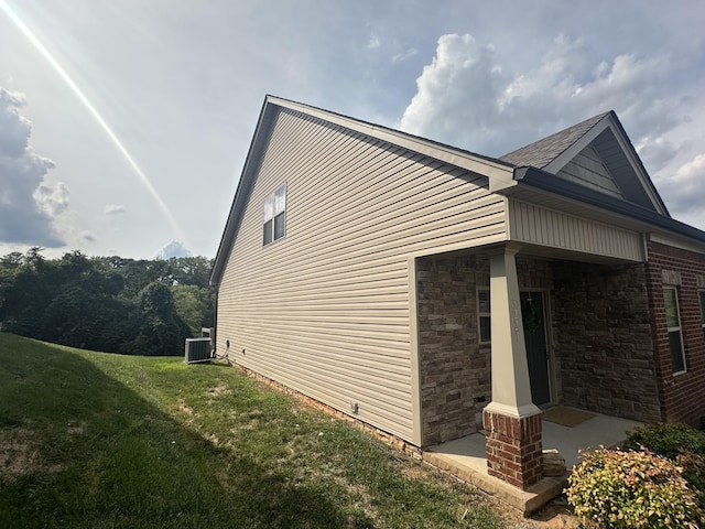 view of side of property featuring central AC unit and a lawn