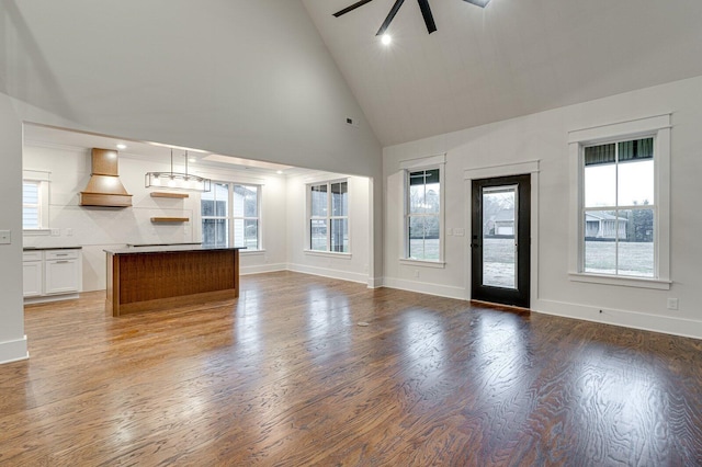 unfurnished living room featuring wood-type flooring, high vaulted ceiling, ceiling fan, and a healthy amount of sunlight