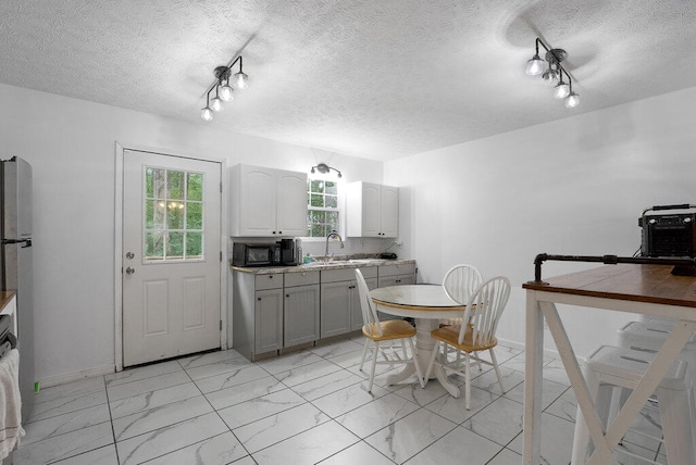 kitchen featuring track lighting, a textured ceiling, sink, and white cabinetry