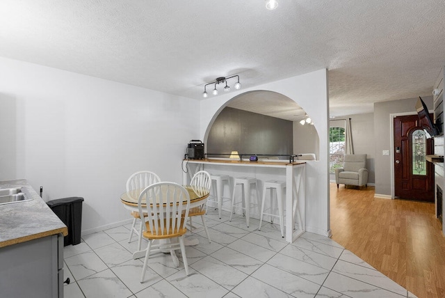 dining area featuring a textured ceiling, light hardwood / wood-style floors, and track lighting