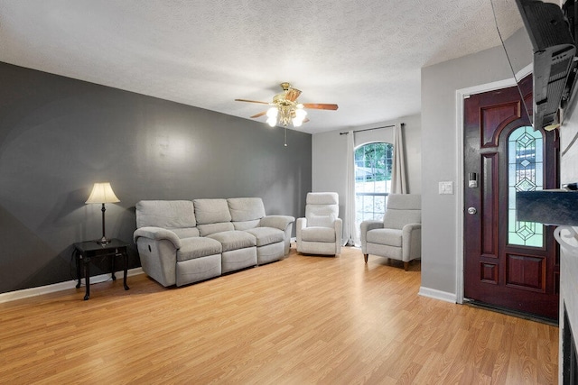 living room with a textured ceiling, ceiling fan, and light hardwood / wood-style flooring