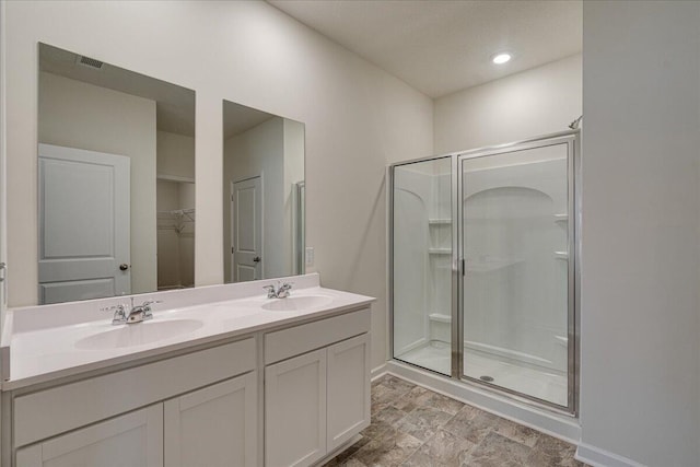 bathroom featuring a shower with door and vanity