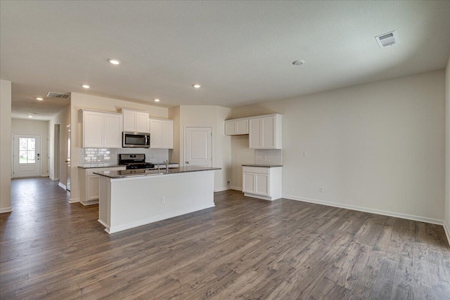 kitchen with white cabinets, an island with sink, stainless steel appliances, and dark wood-type flooring