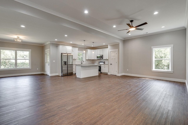 unfurnished living room with crown molding, hardwood / wood-style floors, ceiling fan, and a wealth of natural light