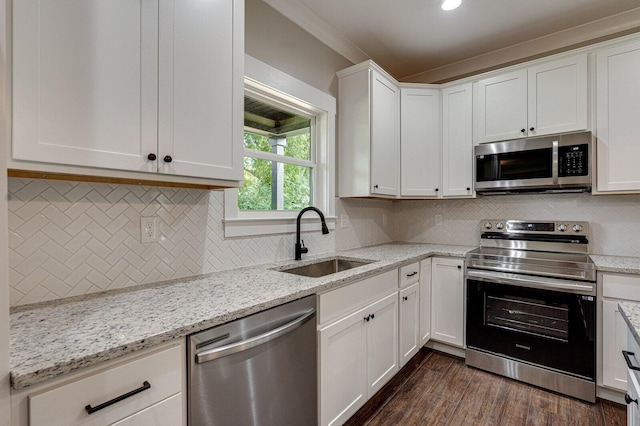 kitchen with light stone counters, sink, white cabinets, stainless steel appliances, and dark hardwood / wood-style flooring