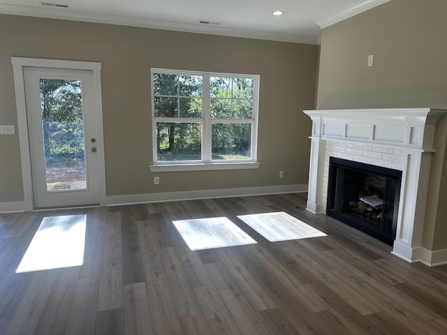 unfurnished living room featuring a brick fireplace, a healthy amount of sunlight, crown molding, and dark hardwood / wood-style flooring